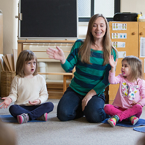 teacher and two children waving
