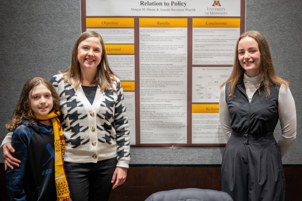 Attendees smiling in front of poster