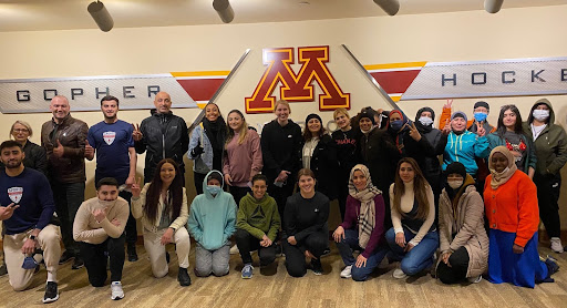 26 Sports Visitor Program participants in group photo in front of the U of M block M logo